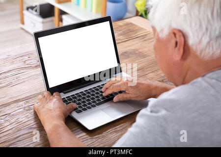 Senior Man Using Laptop With Blank White Screen Stock Photo