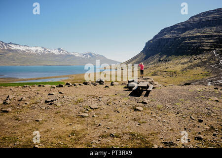 A lone tourist in pink standing in the rugged landscape of the East Fjords region of Iceland. Stock Photo
