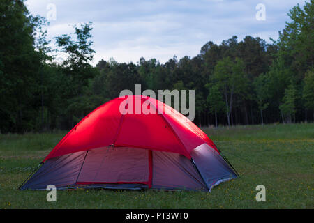Trees behind a tent that is illuminated by something inside Stock Photo