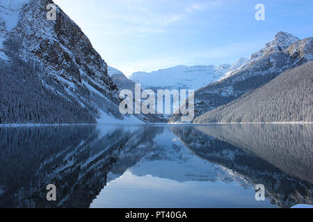 Lake Louise surrounded by snow covered peaks reflected in clear water Stock Photo