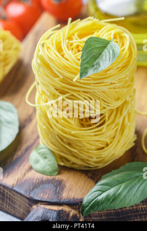 Raw Egg pasta nest - Homemade Capelli d'angelo, Angel's hair. Italian Cuisine. Ingredients for a delicious dinner. Basil, vermicelli, tomatoes,  olive Stock Photo