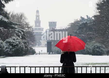 A woman with red umbrella admires the view of Sempione park during a snowfall, Milan, Lombardy, Italy, Europe, Stock Photo