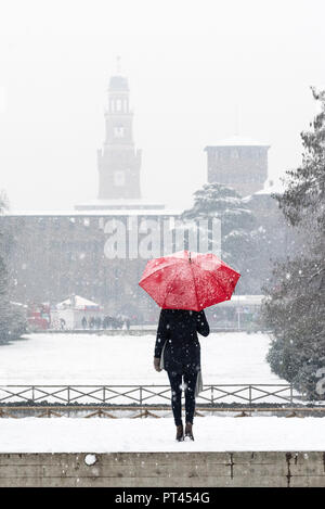 A woman with red umbrella admires the view of Sempione park during a snowfall, Milan, Lombardy, Italy, Europe, Stock Photo