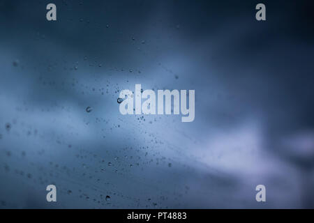 Rain drops on window with dark blue sky Stock Photo
