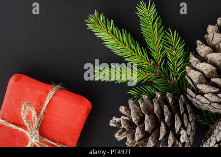 Christmas composition on a black background. Gifts, branches of fir and cones. Stock Photo