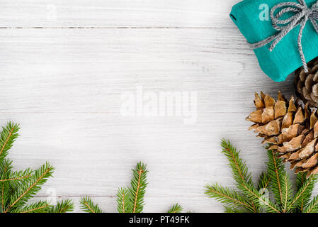 Christmas background - spruce branches, cones and gifts in a kraft paper package. Stock Photo
