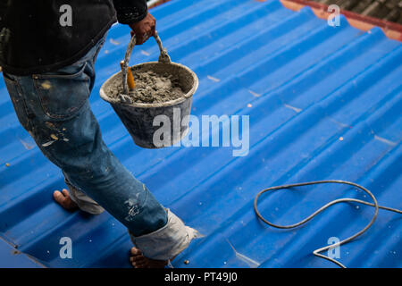 Construction worker on the roof holding a bucket of wet concrete Stock Photo