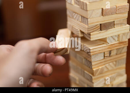 Man pull a wooden block out of the tower Stock Photo