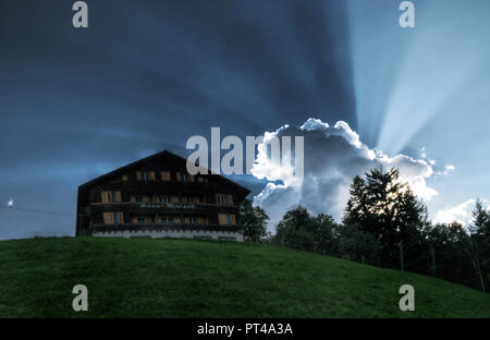 Sunburst over Flumserberg; sun behind cloud projecting dramatic rays in the Swiss Alps Stock Photo