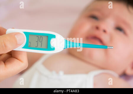 Baby sick with measuring electric thermometer. Child fever ill. Kid catch cold with temperature. Sick child in bed with fever measuring temperature wi Stock Photo