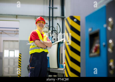 Smiling factory technician beside a machine Stock Photo