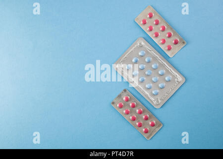 Diagonally arranged blister packs of blue and pink pills on blue background with copyspace- healthcare and medical concept Stock Photo