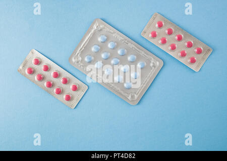 Diagonally arranged blister packs of blue and pink pills on blue background- healthcare and medical concept Stock Photo