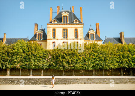 FONTAINBLEAU, FRANCE - August 28, 2017: Fontainebleau palace with young woman running in the garden, France Stock Photo