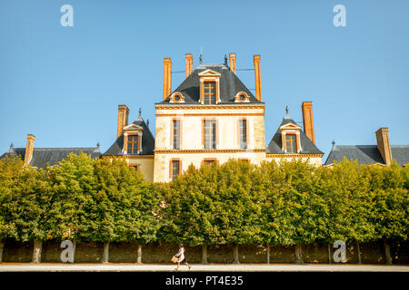 FONTAINBLEAU, FRANCE - August 28, 2017: Fontainebleau palace with young woman running in the garden, France Stock Photo