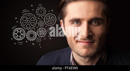 Portrait of a young businessman with rotating gears next to him on a dark background Stock Photo