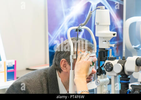 Patient eye doctor checkup patient eyes with apparatus. health care, medicine, people, eyesight and technology concept - man checks his vision on the  Stock Photo