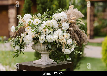 Magnificent flowers and dried flowers in a white vase. Details of a decor of a wedding ceremony under the open sky Stock Photo