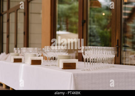 Table with ware for a buffet reception on a terrace of restaurant. Much clean glass glasses for champagne Stock Photo