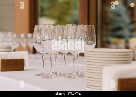 Glasses and white plates on a table at restaurant. Stylish ware for a festive buffet reception Stock Photo