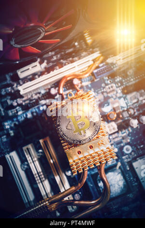 The gold coin of digital crypto currency Bitcoin lies on the motherboard of the computer Stock Photo