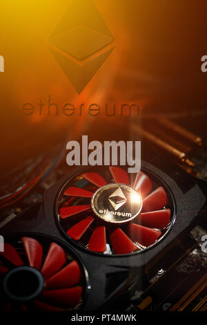 Cryptocurrency mining concept closeup with golden ethereum on top of a computer performant video card red fans Stock Photo