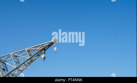 detail of an old harbor crane with pulley and hooks in a clear blue sky Stock Photo