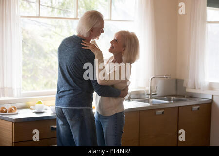 Happy loving senior couple dancing in kitchen, smiling old family having fun embracing at home, mature man and woman relaxing together enjoying tender Stock Photo