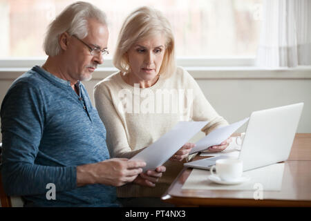 Serious worried senior couple calculating bills to pay or checking domestic finances stressed of debt, retired elderly old family reading documents co Stock Photo