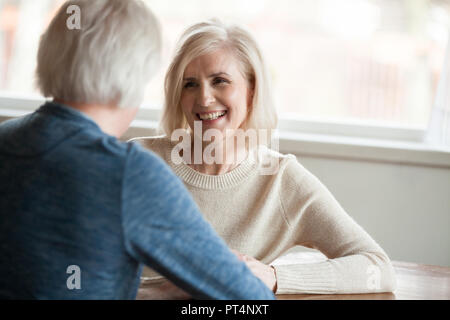 Smiling beautiful mature woman listening to elderly man talking, senior happy retired family enjoying pleasant conversation, senior couple dating conc Stock Photo