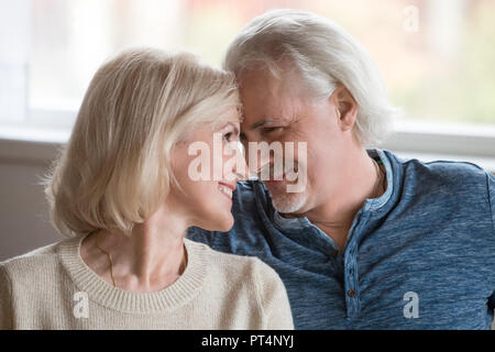 Happy middle aged romantic couple touching noses having fun enjoying sincere love feelings together, smiling senior older family bonding looking at ea Stock Photo