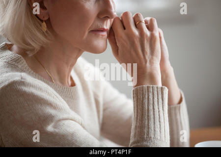 Close up view of thoughtful mature woman worried concerned about problems or disease, middle aged grey haired senior lady getting older thinking of lo Stock Photo