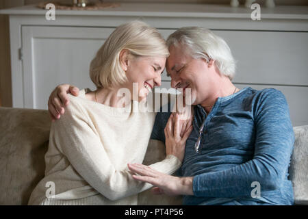 Happy loving mature middle aged romantic couple laughing embracing at home, smiling elderly man hugging senior woman enjoying fun, good relations humo Stock Photo