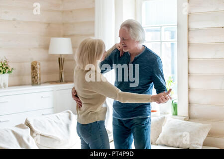 Happy loving mature couple dancing at home in living room Stock Photo