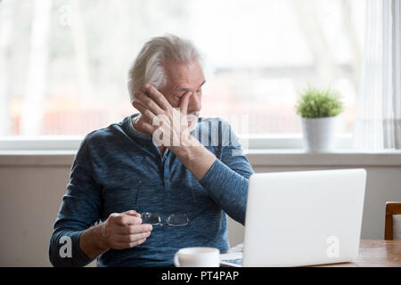 Fatigued mature man taking off glasses suffering from tired eyes Stock Photo