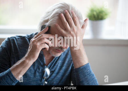 Frustrated mature man feeling upset desperate talking on the pho Stock Photo