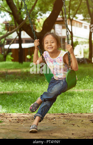 Asian girl on a swing playing at a park. Filipina kid playing in a park. Stock Photo