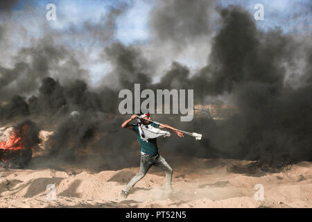 A palestinian demonstrator seen throwing stones at Israeli troops east of Khuza'a in southern Gaza. Hundreds of palestinian demonstrators burn tyres and throw rocks using slingshots in response to Israeli forces' intervention during a demonstration within the 'Great March of Return' on the Gaza-Israel border. Stock Photo