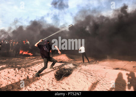 A palestinian demonstrator seen using a slingshot to throw stones at Israeli troops east of Khuza'a in southern Gaza. Hundreds of palestinian demonstrators burn tyres and throw rocks using slingshots in response to Israeli forces' intervention during a demonstration within the 'Great March of Return' on the Gaza-Israel border. Stock Photo