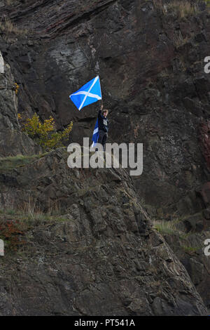 Edinburgh, UK. 6th, October, 2018. Edinburgh, Scotland, UK, Europe. A man stands alone on top of a rock at Arthur's seat waving a Scottish flag where over 100,000 people were estimated to be marching below in support for a second independence referendum. Stock Photo