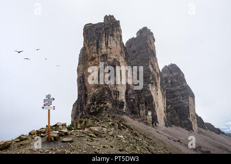 Signpost for hikers next to the famous Tre Cime peaks in the Dolomite mountains on a foggy day, Tuesday 14 August 2018, Tre Cime National Park, Italy. Stock Photo