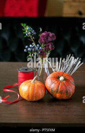 still life with pumpkins, ribbon, blueberries and sedum in a vase on the table Stock Photo