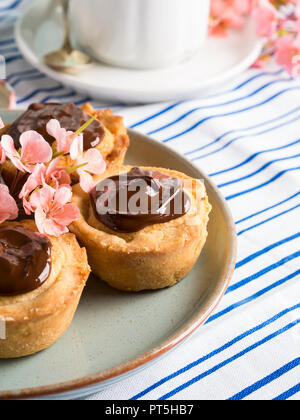 Cakes with frangipane, cherry jam and chocolate frosting. Romantic table setting with flowers. Mother's day card Stock Photo