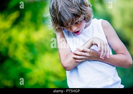 Young boy scratching arm.