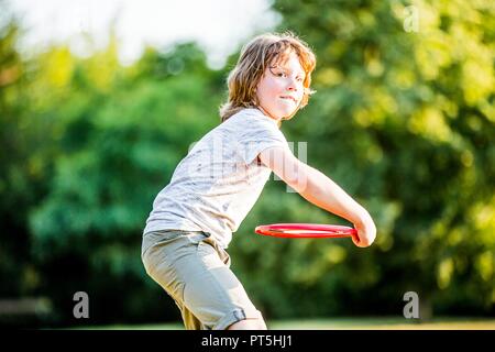 Boy throwing flying disc in park. Stock Photo