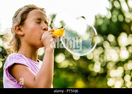 Girl blowing bubbles with bubble wand in park. Stock Photo