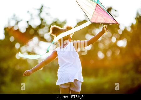 Girl holding kite and running in park. Stock Photo