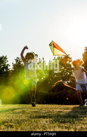 Boys holding kite and running in park. Stock Photo