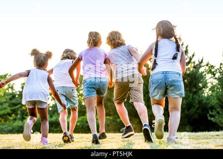 Children holding hands and running in park. Stock Photo