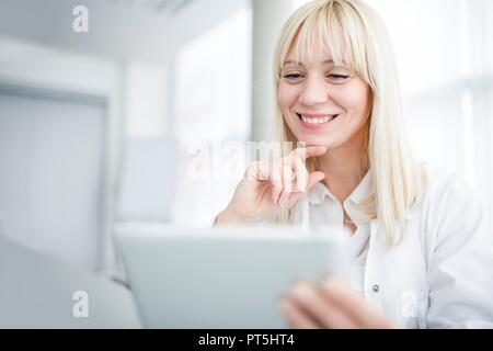 Female doctor using tablet and smiling. Stock Photo